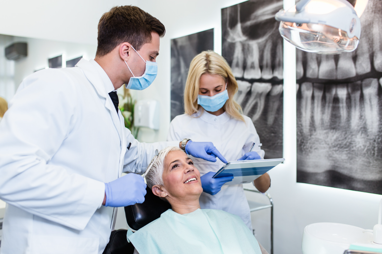 Dentists looking at dental implant trends of 2022 with smiling patient.